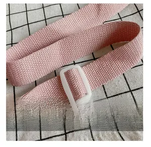 Detailed close-up of a pink woven adjustable shoulder strap with white plastic buckle