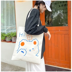 Outdoor shot of a white canvas tote bag with a cute bear and Hi print on a model