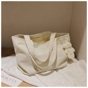 Detail of off-white corduroy tote bag showing soft texture and cute teddy bear pendant