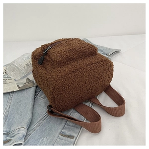 Detailed view of mini brown faux shearling backpack on a casual denim background