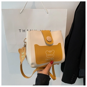 Detail of two-tone bucket bag featuring cartoon bear illustration and a bear charm