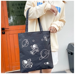 Detail of black canvas tote bag featuring white astronaut and space exploration graphics