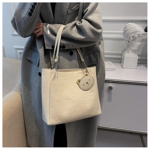 Detail of white embossed tote bag with heart patterns and gold metal strap rings