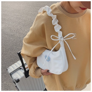 White nylon shoulder bag with ruffled strap and blue heart patch on a yellow sweatshirt