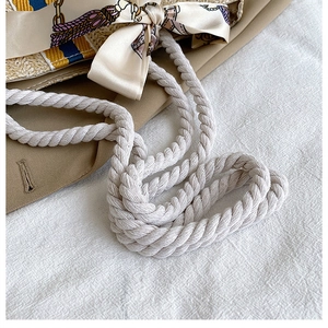 Close-up of woven straw tote with cotton rope strap and yellow floral silk scarf detail