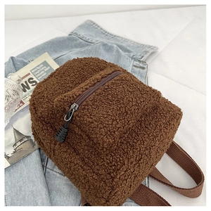 Detail of a brown fuzzy teddy fleece mini backpack with zipper on denim background