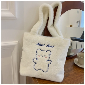 Détail du sac cabas en peluche blanche avec broderie ours bleu et large poignée en fourrure