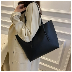 Close-up of a large black minimalist tote bag in soft leather on a female model