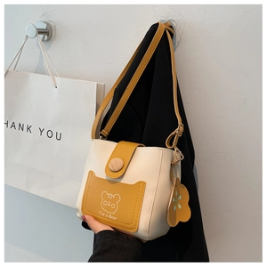 Detail of mini PU leather bucket bag featuring a cartoon bear print and wooden button