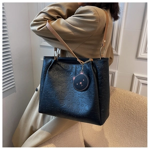 Detail of black faux leather tote with embossed cartoon motifs and brown straps