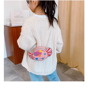 Détail du sac à bandoulière en forme de bonbon rose avec des pois porté par un enfant