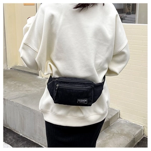 Detailed view of black corduroy chest bag with vintage texture and white woven label
