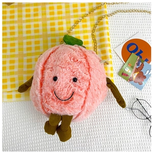Detail of cute plush peach bag with smiley face embroidery and green leaf accent