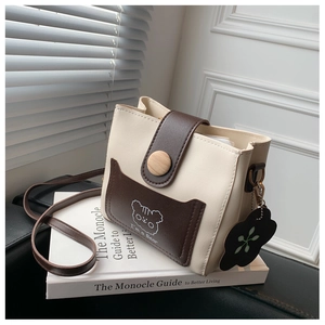Macro view of bicolor crossbody bag featuring a wooden button and cartoon bear print