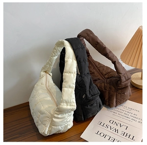 Close-up of three quilted underarm bags in beige black and coffee on a wooden table