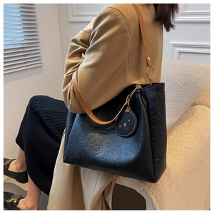 Detail of black tote bag with cartoon embossed patterns and brown leather strap