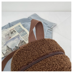 Detail of brown teddy fleece backpack with woven handle and smooth zipper texture