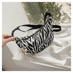 Close-up of zebra pattern crescent bag with adjustable strap and cute cow charm