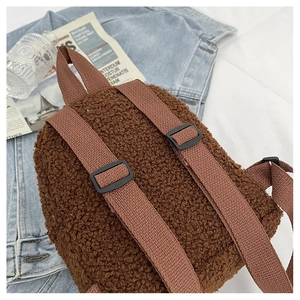 Detail of soft brown faux shearling backpack with adjustable straps on denim background