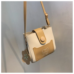 Detail of mini color-block bucket bag with cute bear print and floral tag accessory