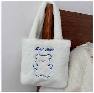 Détail du sac cabas en peluche blanche avec broderie d'ours bleu et texte Beat Beat