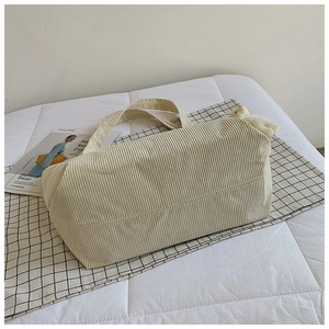 Close-up of cream corduroy tote bag texture with a cute plush bear charm accessory