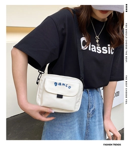 Detail of white nylon crossbody bag with blue Dance embroidery and black adjustable strap