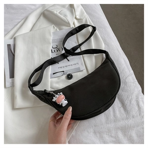 Detail of black nylon half-moon crossbody bag featuring a cute cow charm and adjustable strap