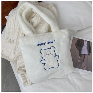 Détail du sac cabas en peluche blanche avec broderie d'ours bleu et texte doux