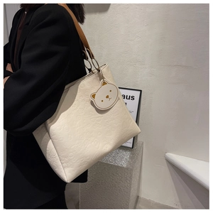 Detail of embossed cartoon pattern on white faux leather tote bag with brown straps