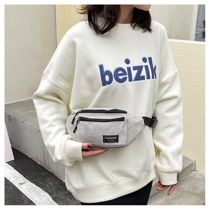 Detail of grey corduroy chest bag featuring black zipper and Fashion Instinct label