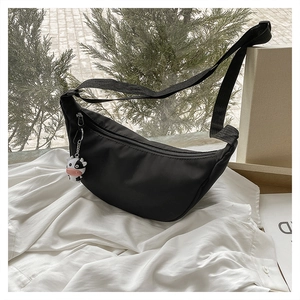 Detail of black nylon half-moon crossbody bag with cute cow pendant and wide strap