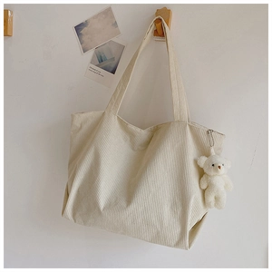 Detail of off-white corduroy tote bag texture with a cute plush bear charm