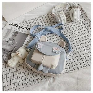 Detail of blue canvas bunny bag with bear charm on a stylish grid background