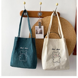 Dettaglio di borse tote in velluto a coste verde e beige con ricamo di orso carino