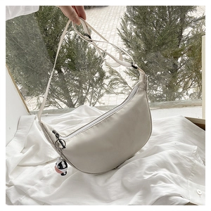 Detail of a beige nylon hobo bag with wide shoulder strap and cute cow charm