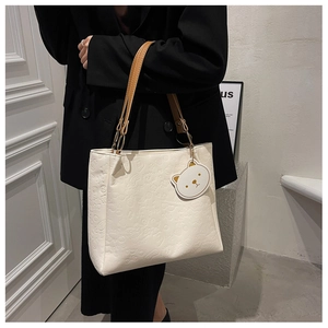 Detail of white tote bag with embossed cartoon patterns and brown leather handles