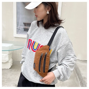 Outdoor shot of a brown corduroy crossbody chest bag with adjustable black strap