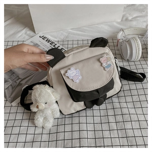 Detail of canvas crossbody bag with 3D animal ears and a plush bear pendant charm