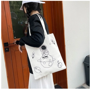 Detail of white canvas tote bag featuring a cute black astronaut print for women