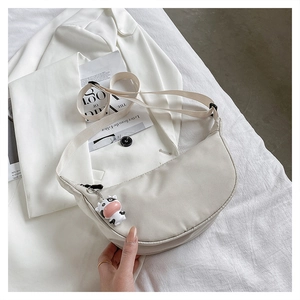 Detail of beige nylon half-moon crossbody bag with cow charm and adjustable wide strap