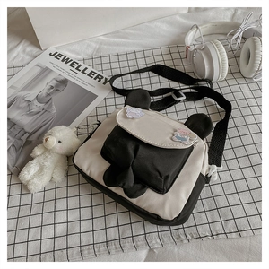 Detail of cartoon shoulder bag with bear pendant on checkered cloth and magazine