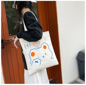 Detail view of the cute blue cartoon bear print on a white canvas tote shoulder bag