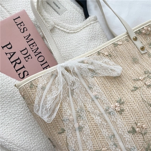 Straw tote bag with floral embroidery and a large white lace bow in a French style