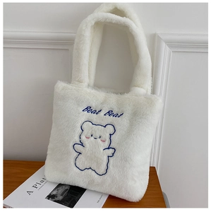 Gros plan du sac fourre-tout en peluche blanche avec broderie d'ours bleu et fausse fourrure