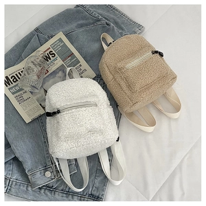 Flat lay of mini faux shearling backpacks in white and tan colors with plush texture