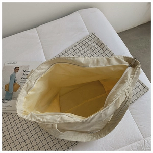 Detail of corduroy tote bag showing large yellow interior capacity and metal zipper closure