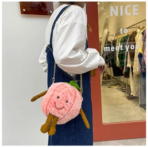 Detail showing plush peach bag with cute black smile and golden metal chain strap