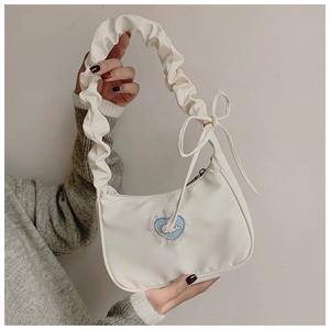 Detail der weißen Plissee-Schultertasche mit blauem Wal-Stickmuster und Spitzenbesatz
