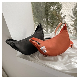Detail of minimalist nylon crescent bags in black and orange with cute cow charms